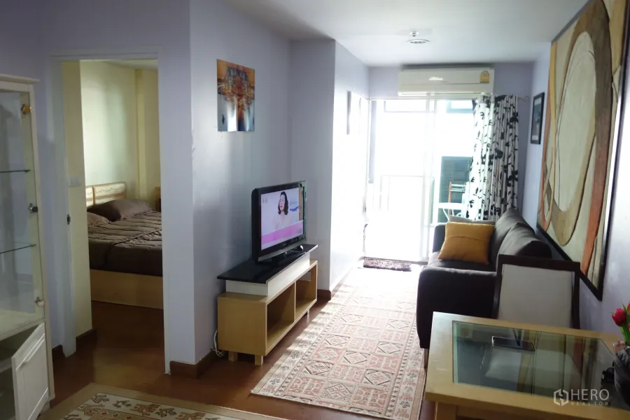 คอนโด ให้เช่าในPhra Khanong, Bangkok - ห้องนั่งเล่นสว่างพร้อมโซฟา ชั้นวางทีวี และประตูเชื่อมระเบียงในคอนโด 1 ห้องนอน