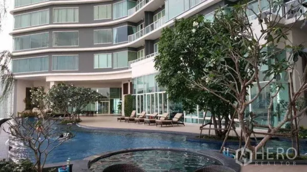 Condominium for rent in Bang Kho Laem, Bangkok - Condominium facade with pool, trees, and glass balconies.