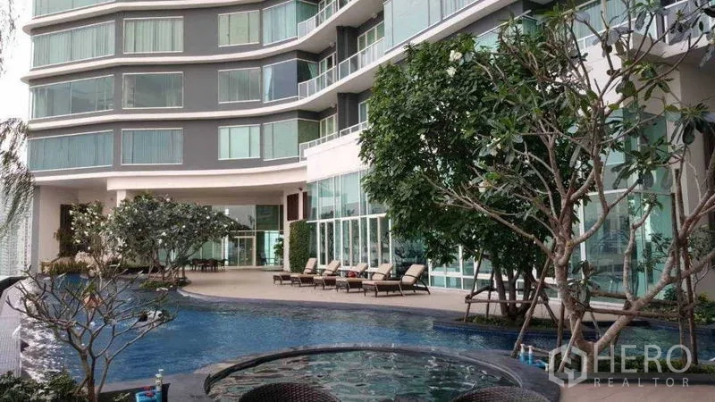 Condominium for rent in Bang Kho Laem, Bangkok - Condominium facade with pool, trees, and glass balconies.