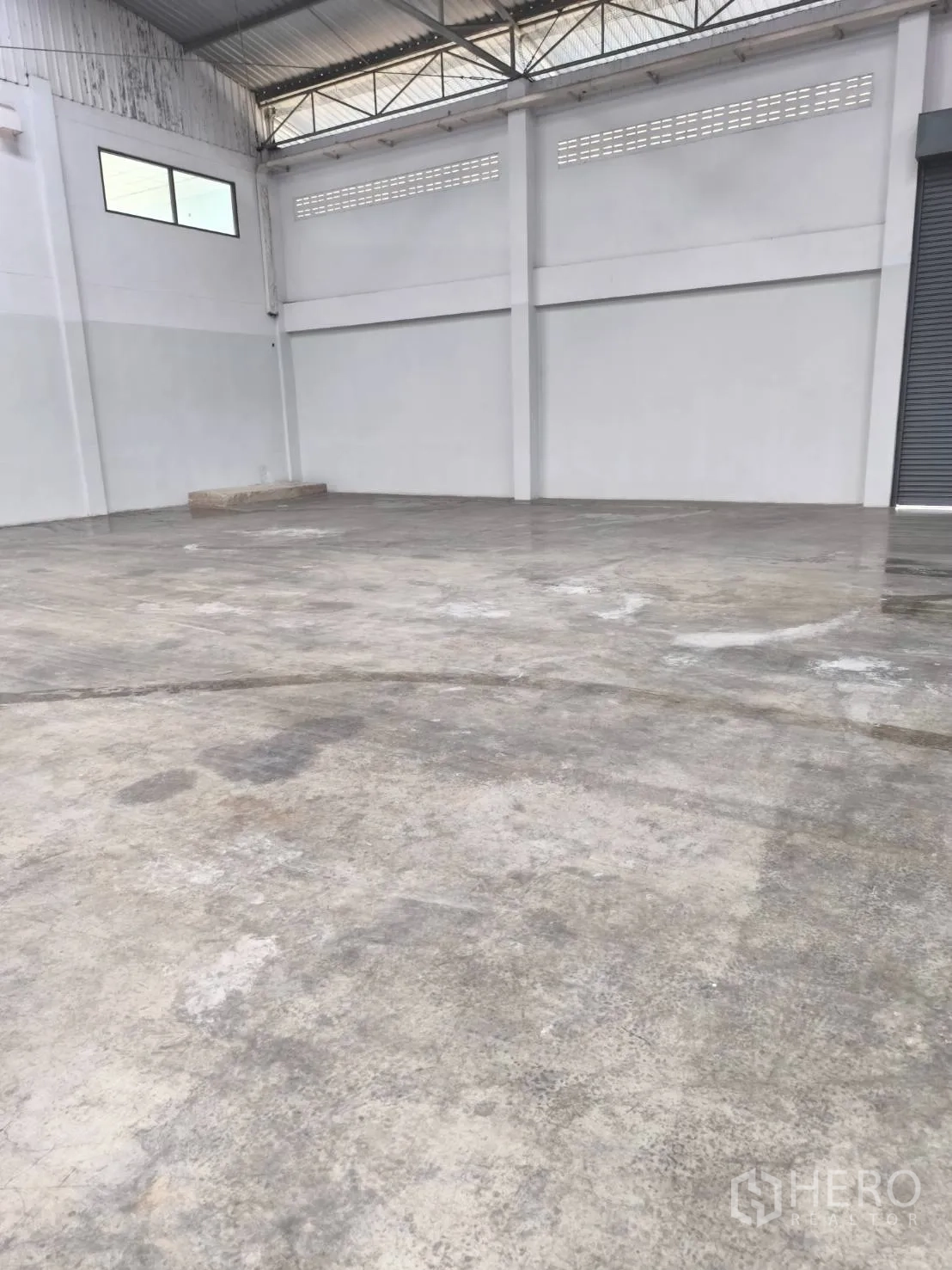 Factory for sale in Khlong Luang, Pathum Thani - High warehouse wall with ventilation blocks and smooth concrete floor.