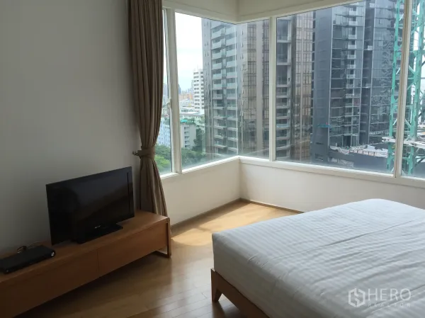 公寓 出租或出售在Watthana, Bangkok - 转角卧室，环绕落地窗享城市景观，配白色床品的床。