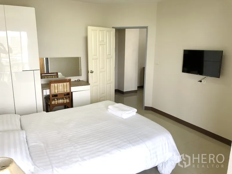Apartment for rent in Suan Luang, Bangkok - Second bedroom featuring a white wardrobe, dressing table and wall-mounted TV.