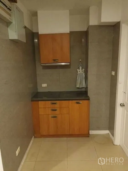 Townhouse for rent in Bang Kapi, Bangkok - Secondary kitchen or pantry with wood cabinets, black countertop, and tiled walls.