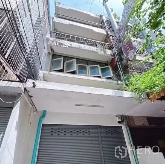 店屋 出租在Bang Rak, Bangkok - 四层店屋外立面，配金属卷帘门与阳台，位于Silom小巷。
