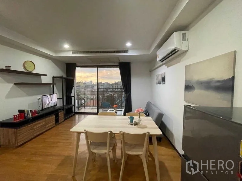 Condominium for rent in Din Daeng, Bangkok - Dining area facing sliding doors to a balcony with skyline views.