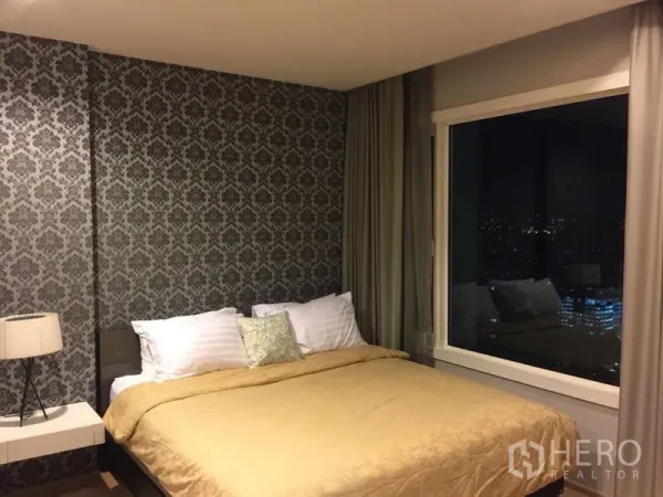 คอนโด ให้เช่าในKhlong Toei, Bangkok - ห้องนอนเตียงควีน วอลล์เปเปอร์ลาย หน้าต่างบานใหญ่พร้อมวิวเมืองยามค่ำ และผ้าม่าน