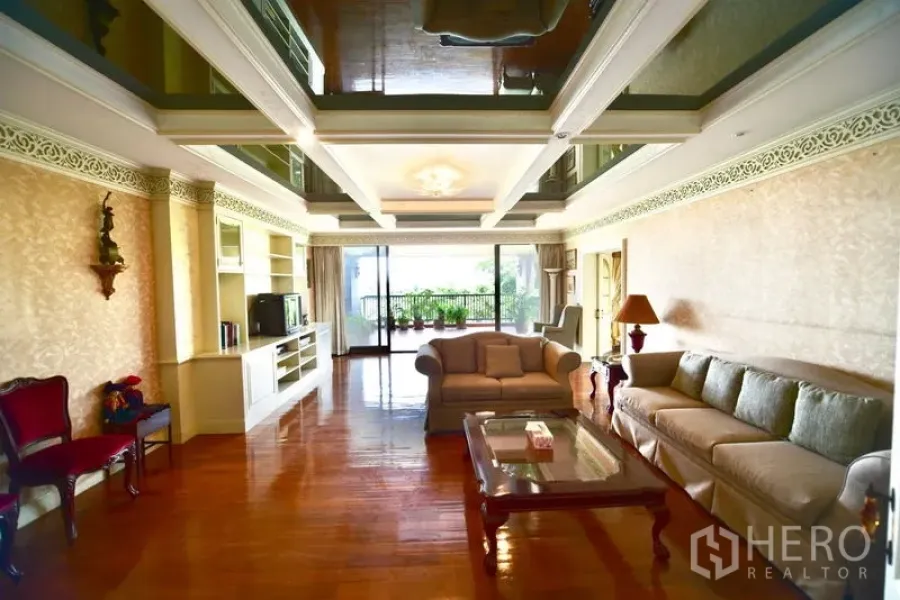 คอนโด ขายในPak Kret, Nonthaburi - ห้องนั่งเล่นกว้าง เพดานฝ้าหลุม พื้นไม้ และประตูบานเลื่อนออกสู่ระเบียงวิวต้นไม้