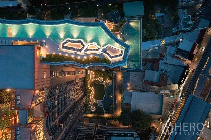 Condominium for sale in Chatuchak, Bangkok - Aerial night view of the high-rise with illuminated rooftop pools and landscaped garden decks.