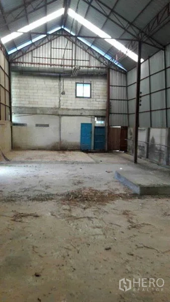货栈 出售在Pathum Thani - 林路甲仓库内部，高挑人字形屋顶、钢梁结构、混凝土地面与蓝色金属门。