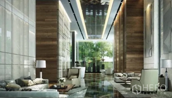 Condominium for rent in Watthana, Bangkok - Luxurious high‑ceiling lobby with marble floors, wood panels and lounge seating.