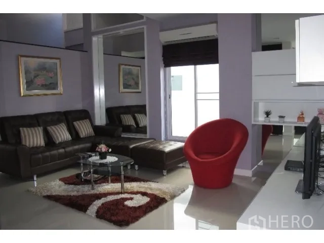 Detached House for rent in Saphan Sung, Bangkok - Bright living room with leather sofa set, red lounge chair, rug, and sliding glass doors.