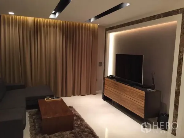 บ้าน ให้เช่าหรือขายในKhlong Toei, Bangkok - ผนังทีวีพร้อมตู้วางสื่อไม้ แสงไฟไลท์ซ่อน และกรอบหินอ่อนตรงข้ามโซฟา