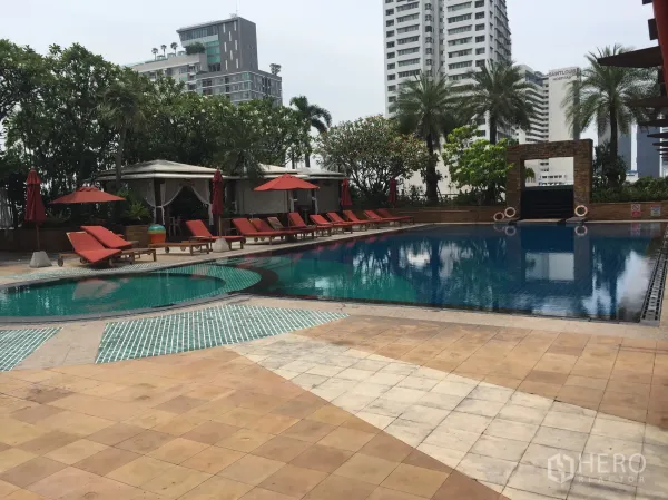 Condominium for rent in Sathon, Bangkok - Resort-style outdoor swimming pool with sun loungers, cabanas, palm trees, and city high-rises near Saint Louis Hospital.