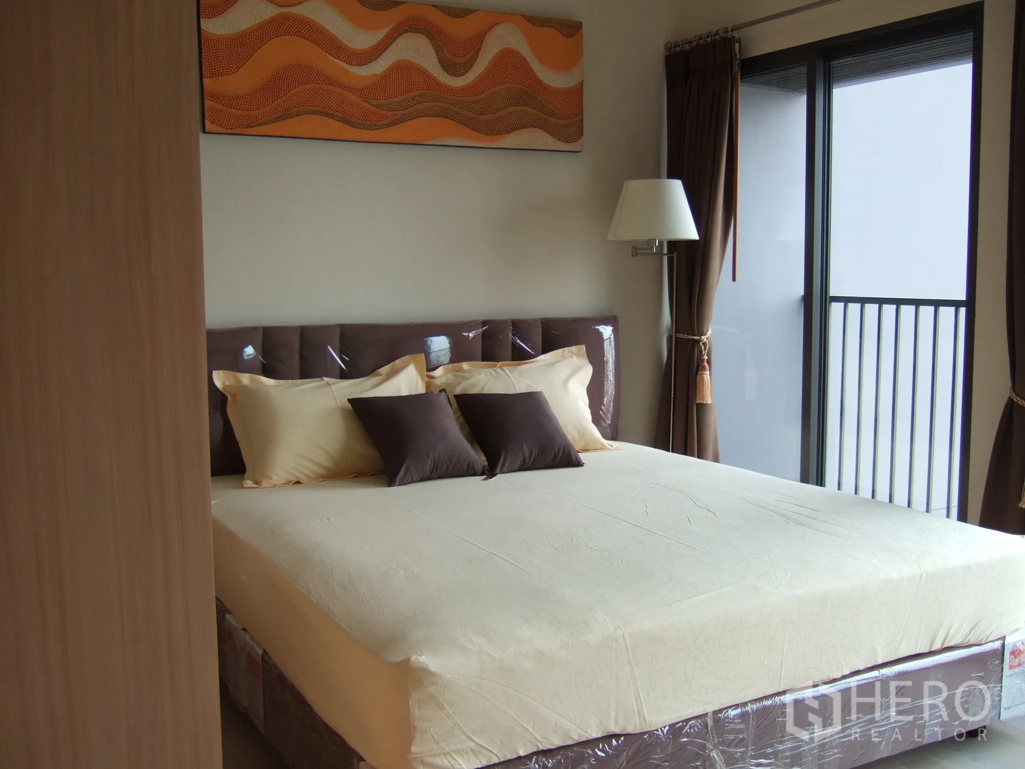 公寓 出租在Khlong Toei, Bangkok - 温馨卧室，大床、棕色窗帘，并可直达私人阳台。
