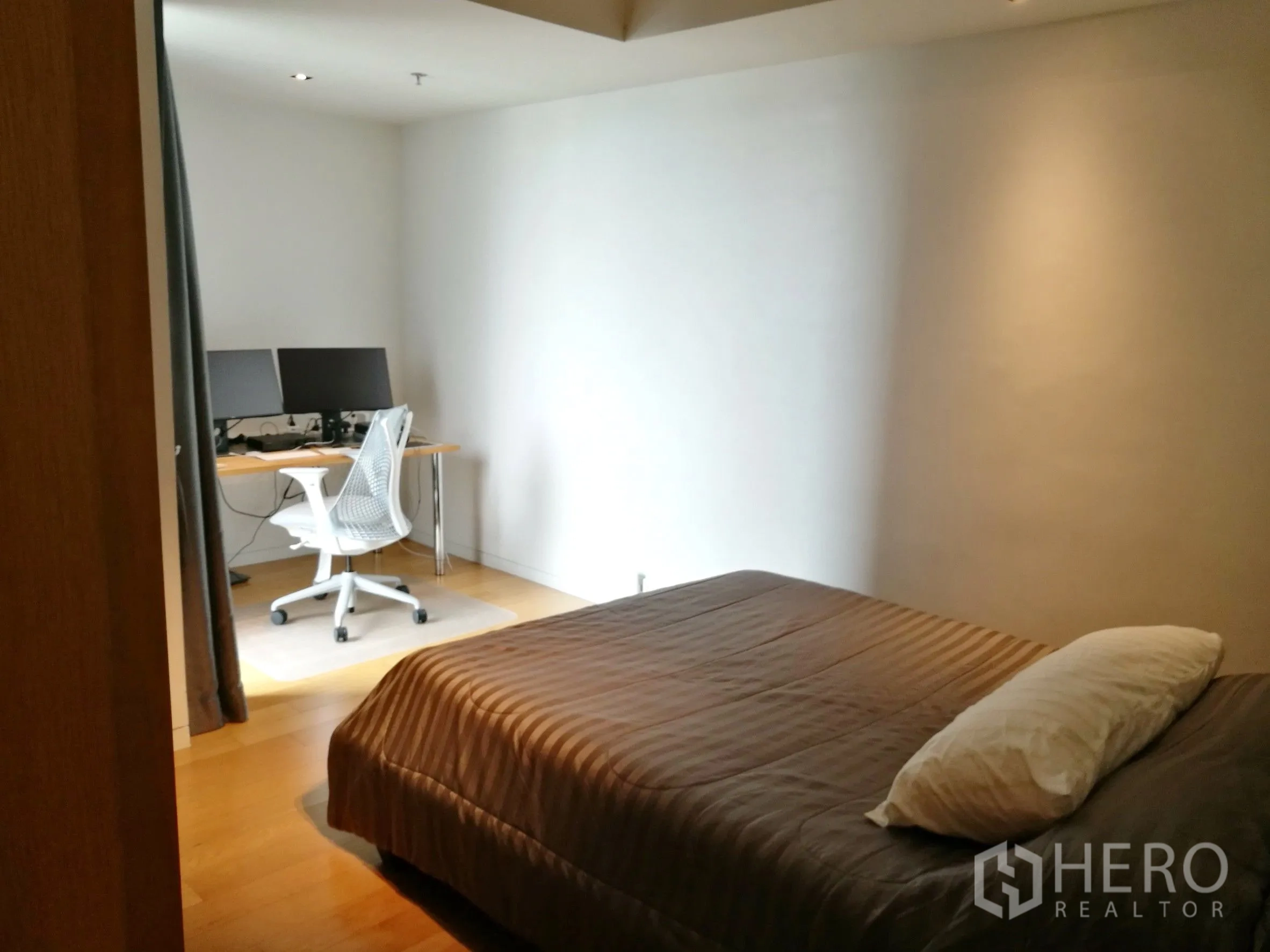 Condominium for rent or sale in Sathon, Bangkok - Bedroom area with a study nook, desk and natural light from a curtained opening.