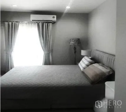 Detached House for rent in Don Mueang, Bangkok - Master bedroom with a large bed, air-conditioning and soft natural light through curtains.