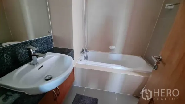 Condominium for rent or sale in Watthana, Bangkok - Bathroom with bathtub, large mirror, and single vanity on a granite countertop.