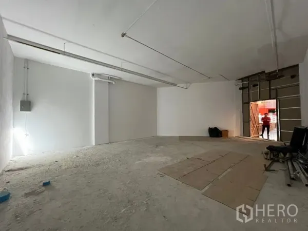 พื้นที่ขายปลีก ให้เช่า - พื้นที่ค้าปลีกแบบเปลือกโล่ง ผนังสีขาว พื้นคอนกรีต ไฟยาว และช่องหน้าร้านกว้าง พร้อมปรับแต่ง