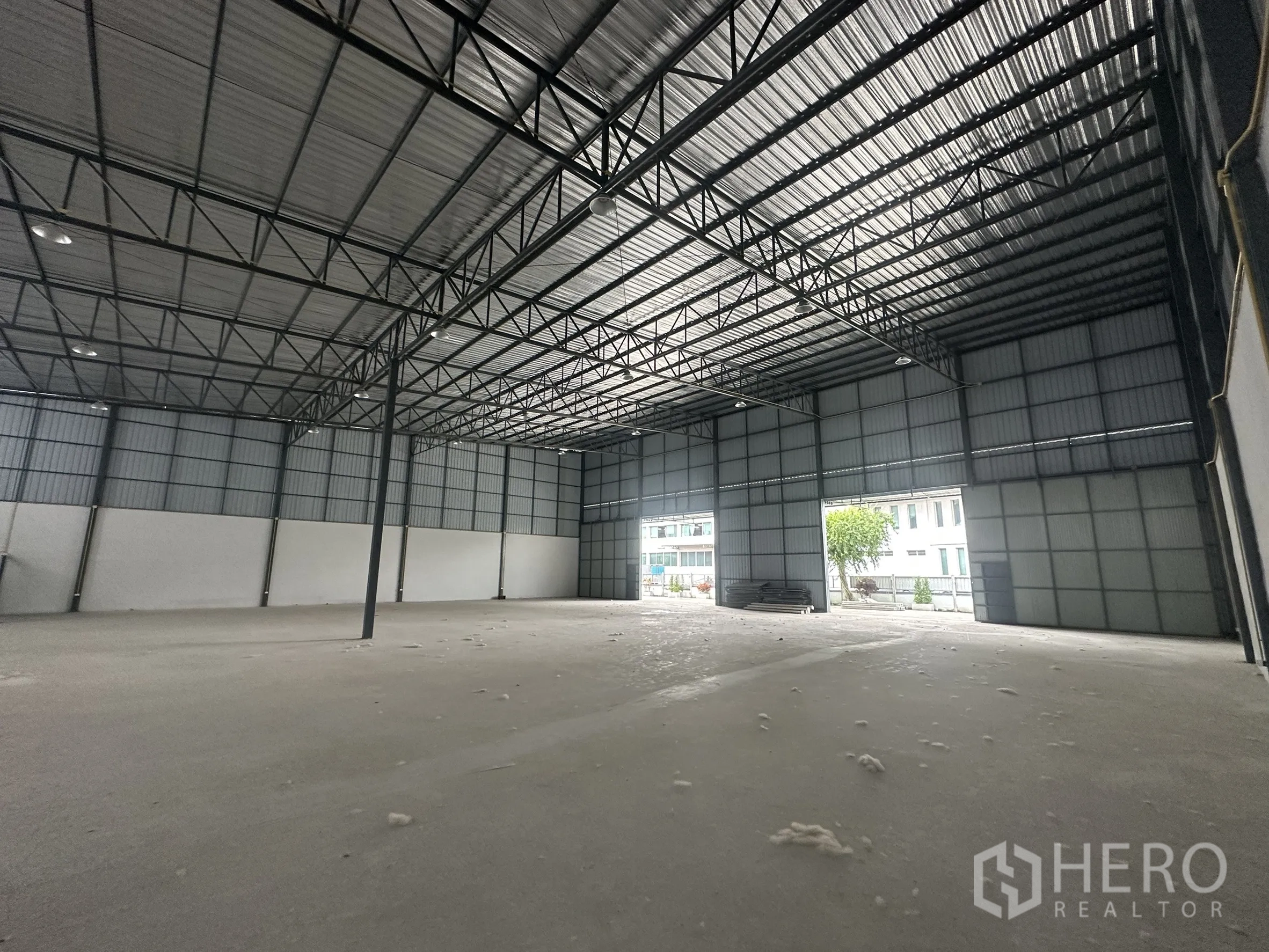 Warehouse for rent in Lam Luk Ka, Pathum Thani - Spacious warehouse interior showing high steel truss roof, concrete floor and large loading openings.