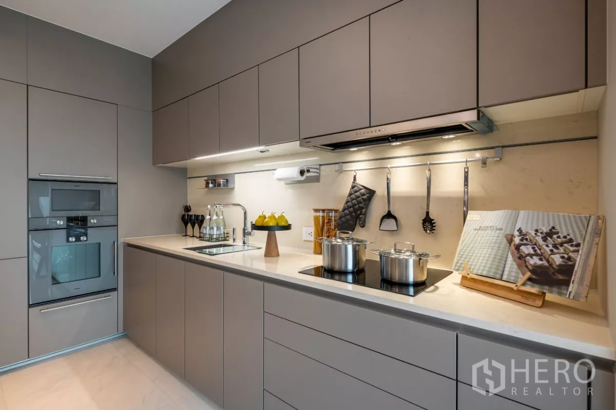 Condominium for rent or sale in Pathum Wan, Bangkok - Fully fitted kitchen with induction hob, sink, under-cabinet lighting and built-in oven.