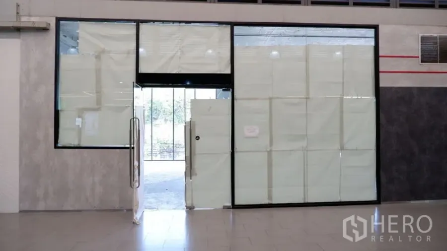 零售空间 出租在Watthana, Bangkok - 室内走廊一侧的玻璃店面与门，装修期遮蔽窗面。