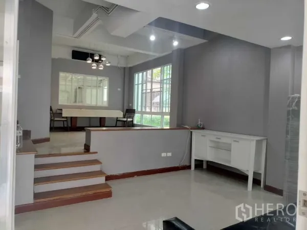 ทาวน์เฮาส์ ให้เช่าในBueng Kum, Bangkok - พื้นที่นั่งเล่นและทานอาหารแบบโอเพ่นพร้อมบันได หน้าต่างบานใหญ่ และผนังสีเทา