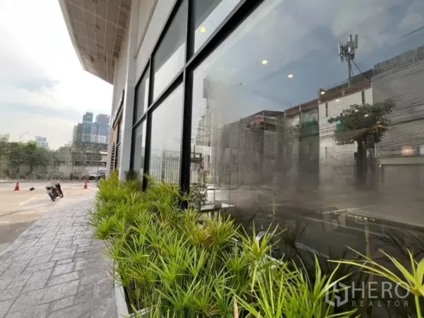 พื้นที่ขายปลีก ให้เช่าในWatthana, Bangkok - มุมด้านนอกติดถนน กระจกเต็มความสูง พร้อมกระบะปลูกต้นไม้และวิวเมือง.