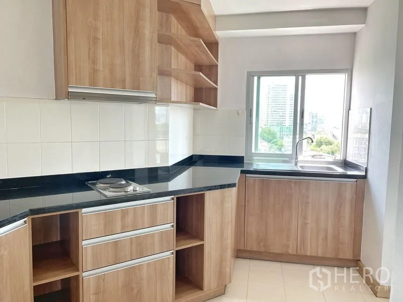 คอนโด ให้เช่าในKhlong Toei, Bangkok - ครัวรูปตัวยู ตู้ไม้ ท็อปหินแกรนิต เตาไฟฟ้า และหน้าต่างรับแสง