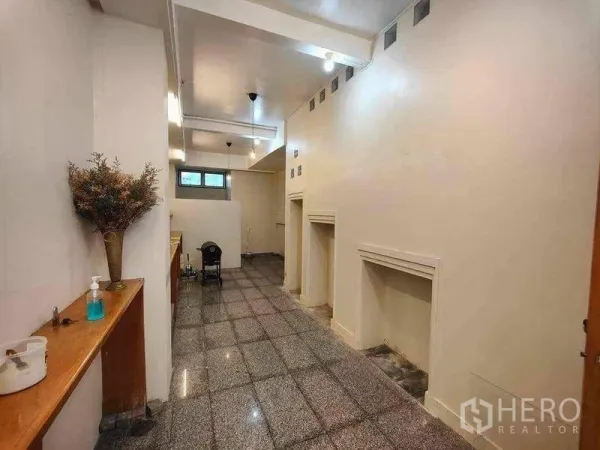 零售空间 出租在Khlong Toei, Bangkok - 高挑零售大厅，墙面展示凹槽与射灯，后侧小窗采光。