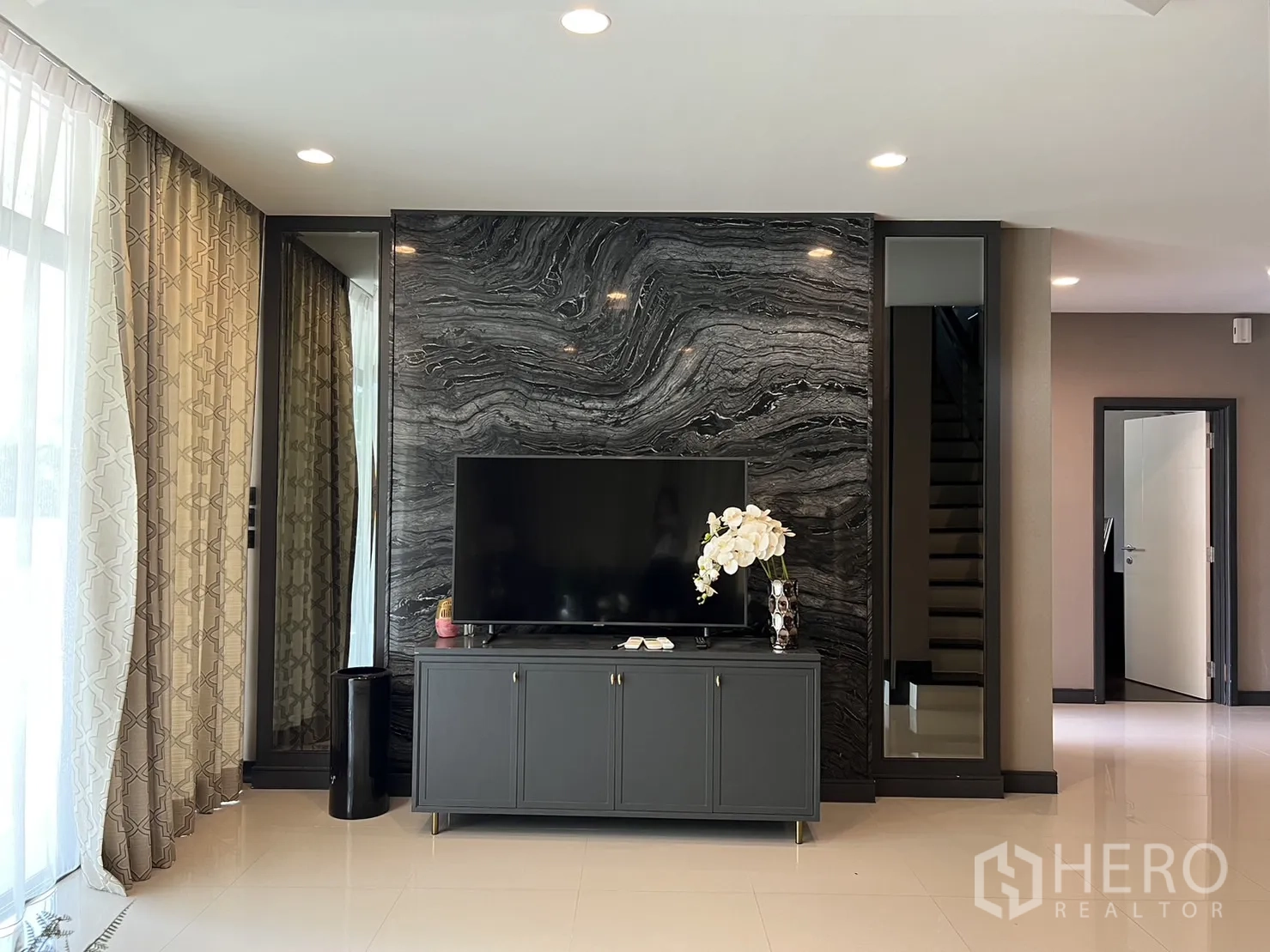 Detached House for rent or sale in Bang Kapi, Bangkok - TV console set against a wavy marble feature wall near the staircase.