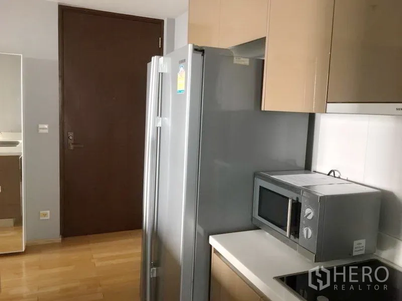คอนโด ให้เช่าในKhlong Toei, Bangkok - ครัวขนาดกะทัดรัดสไตล์โมเดิร์นพร้อมตู้เย็นสแตนเลส ไมโครเวฟ เตาไฟฟ้า และตู้แขวนเงา