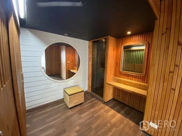 Condominium for rent or sale in Suan Luang, Bangkok - Dressing area with round feature mirror, built-in vanity, wood walls and glass shower entrance.