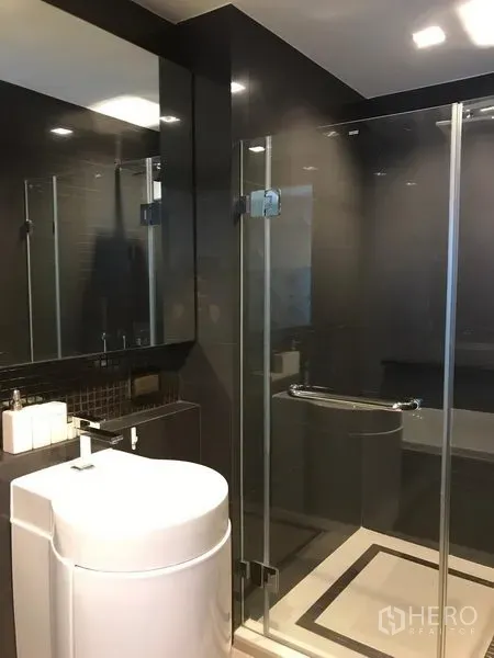 公寓 出租在Sathon, Bangkok - 现代浴室，玻璃淋浴房与深色瓷砖、时尚洗手台
