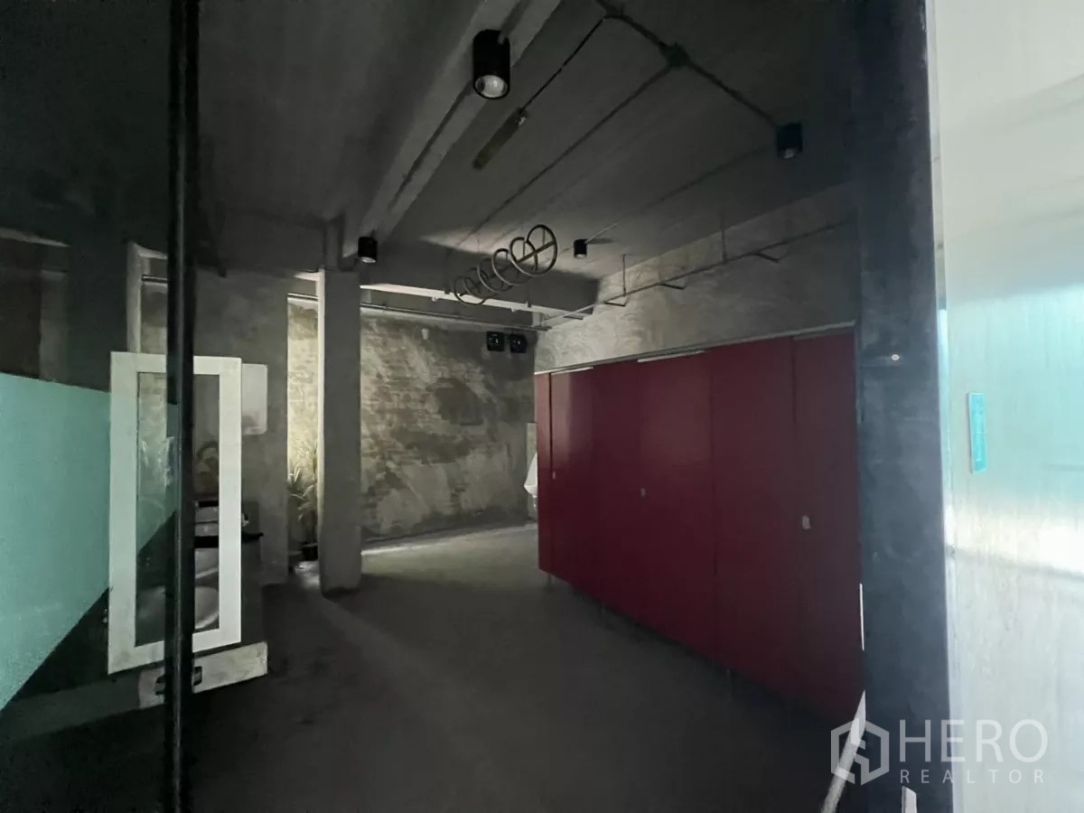 独立商业地产 出租在Din Daeng, Bangkok - 工业风走廊，裸砖墙与红色柜体，光线柔和。