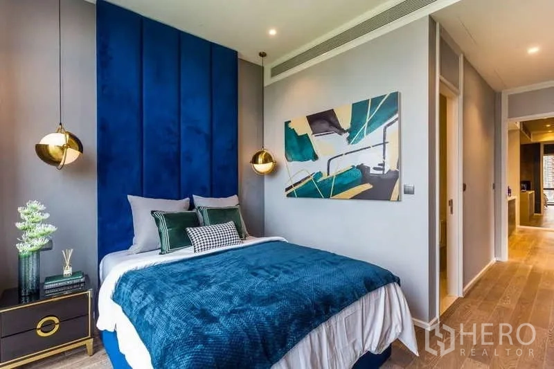 Condominium for rent in Pathum Wan, Bangkok - Master bedroom with tall blue upholstered wall and pendant lights.