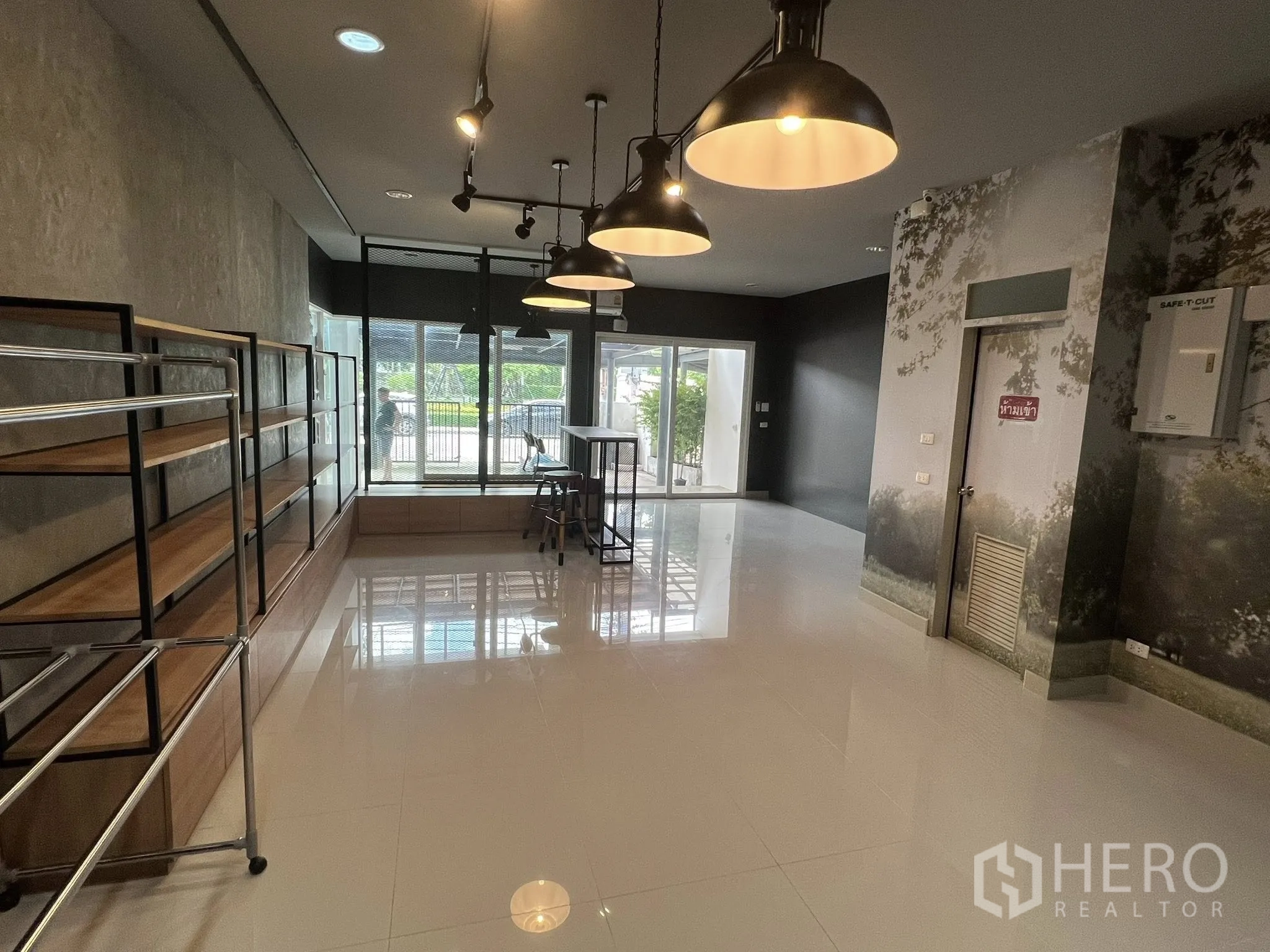 Detached House for rent or sale in Don Mueang, Bangkok - Ground floor showroom with shelving, pendant lights and glass entry.