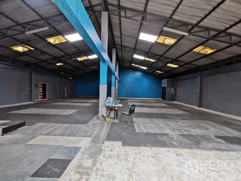 货栈 出租在Nonthaburi - 宽大的仓库分区，中间立柱与蓝色背景墙，地面多色地砖。