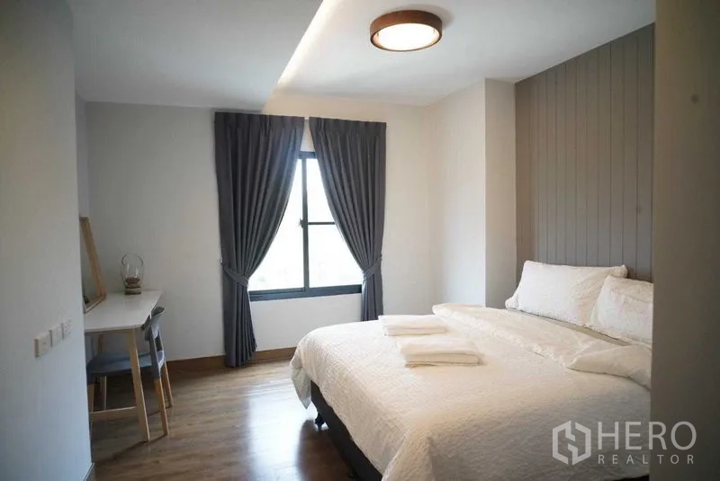 Condominium for rent in Watthana, Bangkok - Bright bedroom with a king bed, study desk and grey drapes.