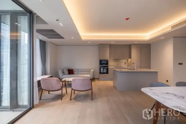 คอนโด ให้เช่าในPathum Wan, Bangkok - มุมนั่งเล่นสบาย ๆ โซฟาและเก้าอี้อาร์มเชร์ริ่ง ข้างกระจกสูงจากพื้นจรดเพดาน วิวเมือง