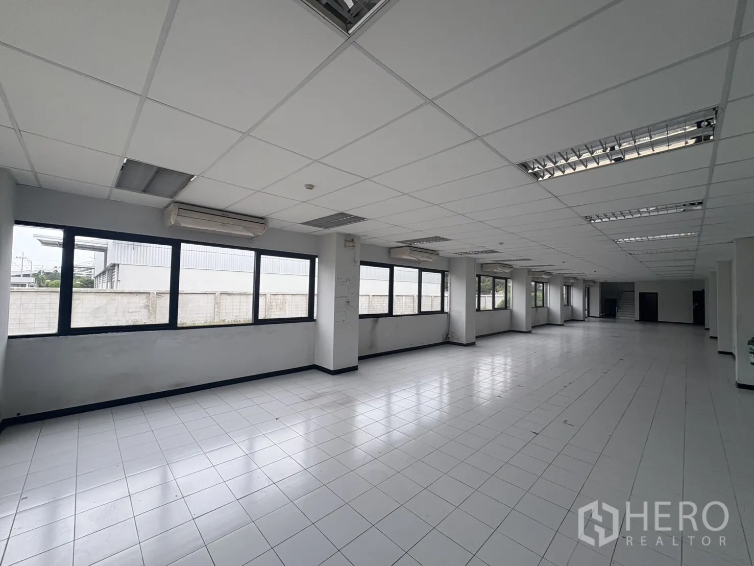 Factory for rent or sale in Samut Prakan - Interior stairwell with white tiled steps and stainless handrail.