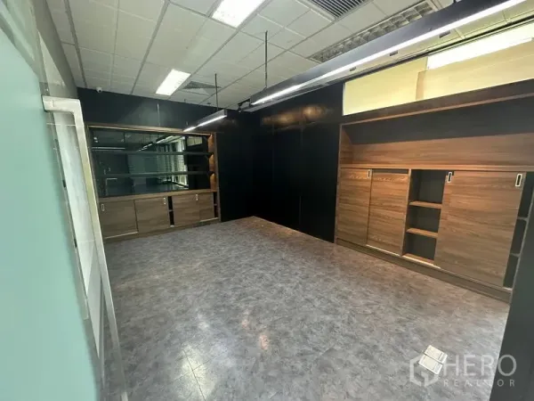 Office Space for rent - Private office with dark accent walls, built-in wood cabinets and shelving, and linear pendant lights.