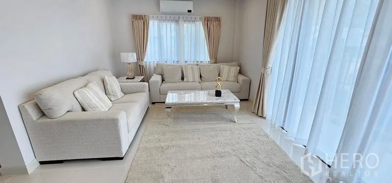 Detached House for rent - Ground-floor living room with two cream sofas, a marble coffee table and sheer curtains.