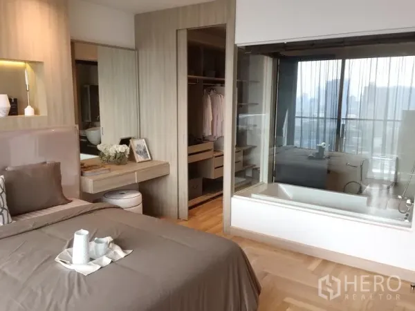 คอนโด ขายในWatthana, Bangkok - ห้องนอนหลักเชื่อมตู้เสื้อผ้าแบบวอล์กอิน และห้องน้ำผนังกระจกพร้อมอ่างอาบน้ำ วิวเมือง