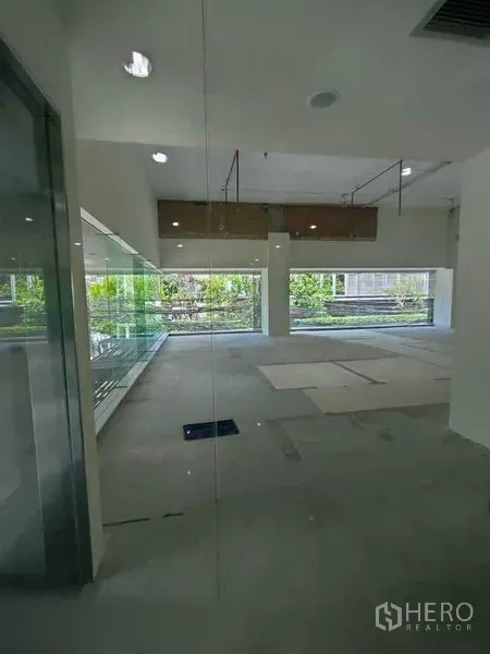 零售空间 出租在Khlong Toei, Bangkok - 明亮的空置商铺，落地窗与外部绿景，高挑裸顶。