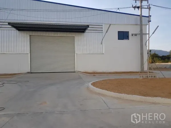 工厂 出租在Chon Buri - 现代工厂外立面，宽幅卷闸门与混凝土车道