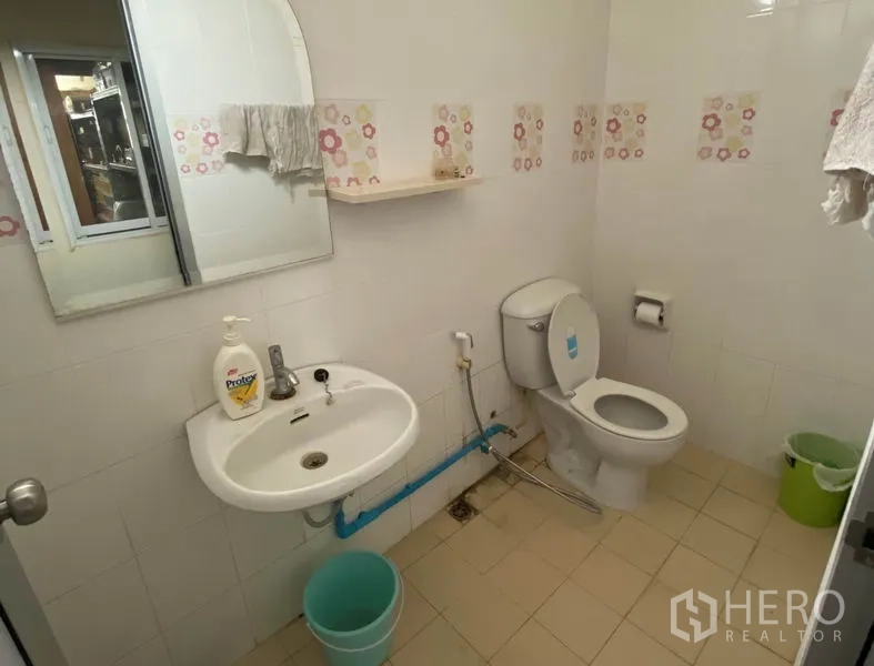 Factory for sale in Khlong Luang, Pathum Thani - Clean tiled restroom with toilet, sink and mirror inside the facility.