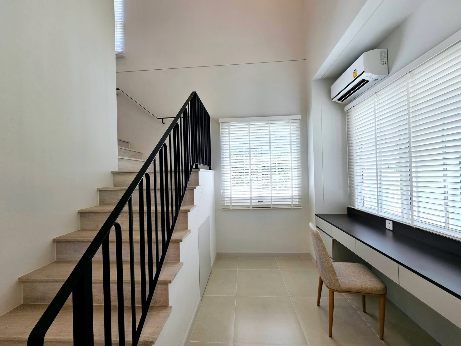 Detached House for rent in Bang Phli, Samut Prakan - Staircase with black metal railing and a study nook under large windows.