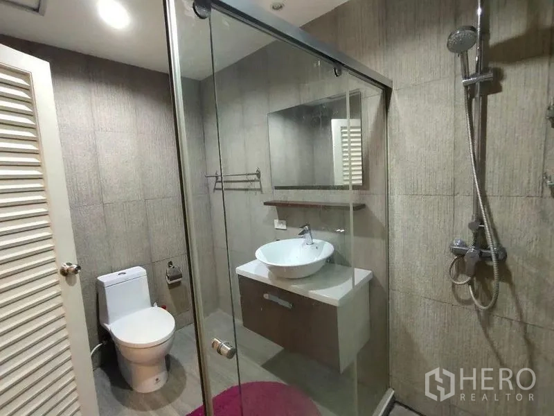 Condominium for rent or sale in Bang Rak, Bangkok - Modern bathroom featuring glass shower enclosure, rain shower, and vanity.