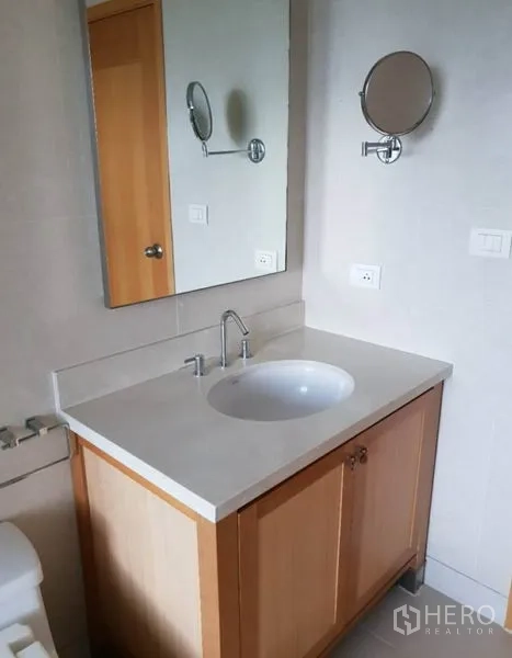 คอนโด ให้เช่าในKhlong Toei, Bangkok - เคาน์เตอร์อ่างล้างหน้าในห้องน้ำ กระจกบานใหญ่ และตู้เก็บของลายไม้