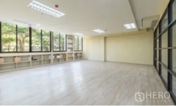 办公空间 出租在Chatuchak, Bangkok - 宽敞办公区，大面积窗户与低矮置物架，木纹地面，顶灯与玻璃隔断。